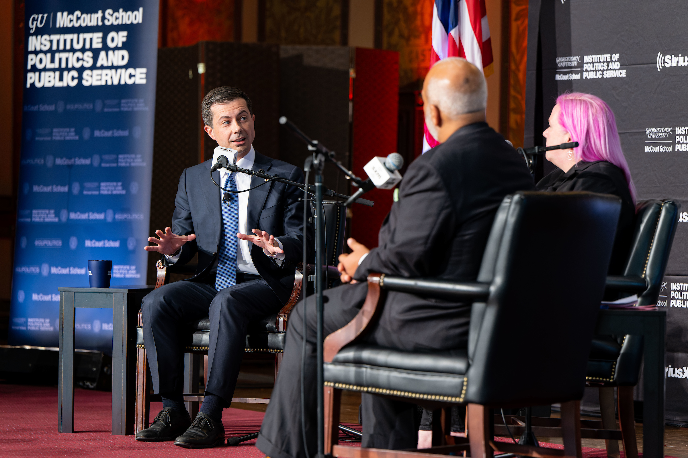 Pete Buttigieg talks into a microphone while seated onstage
