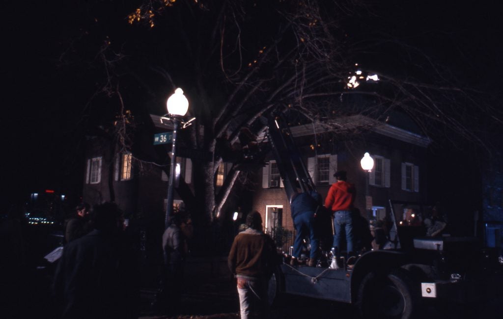 A photo of The Exorcist house in the Georgetown campus with movie production staff on the street