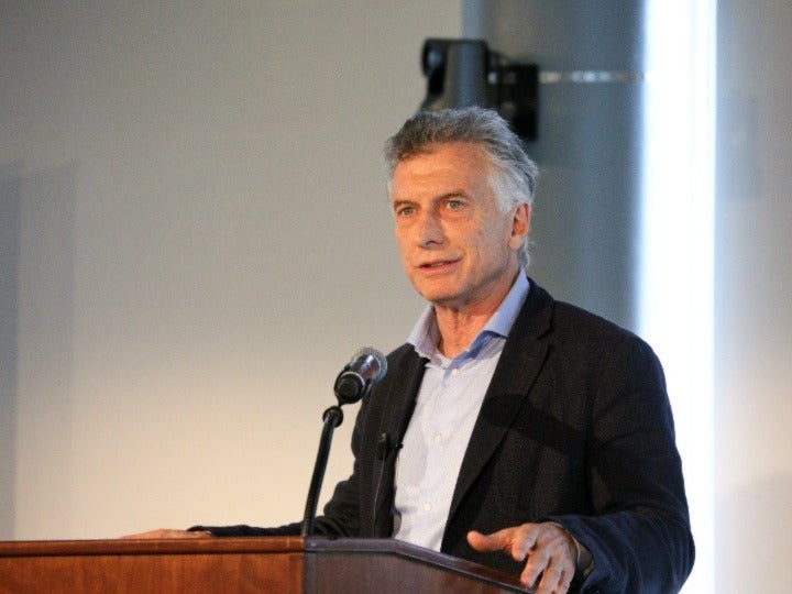 Mauricio Macri wearing a blazer speaks from behind a podium