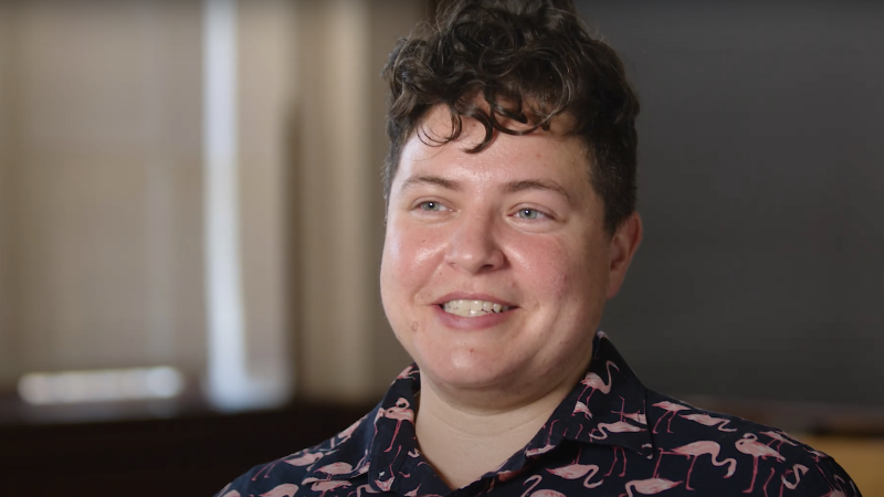 Amanda Phillips has short hair and smiles in a classroom while wearing a collared shirt with flamingos