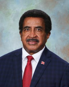 Man with a mustache wears a suit and red tie