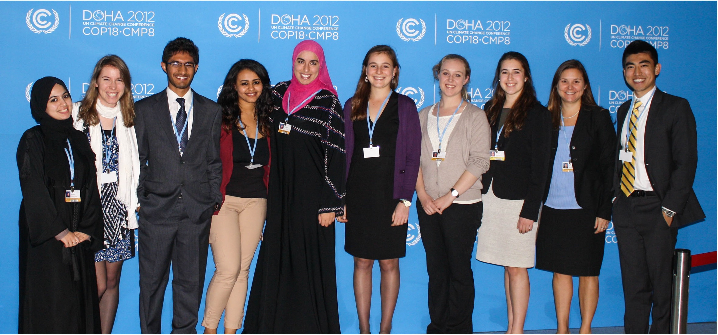 10 students stand next to each other in front of a blue background at a COP18 conference in Doha