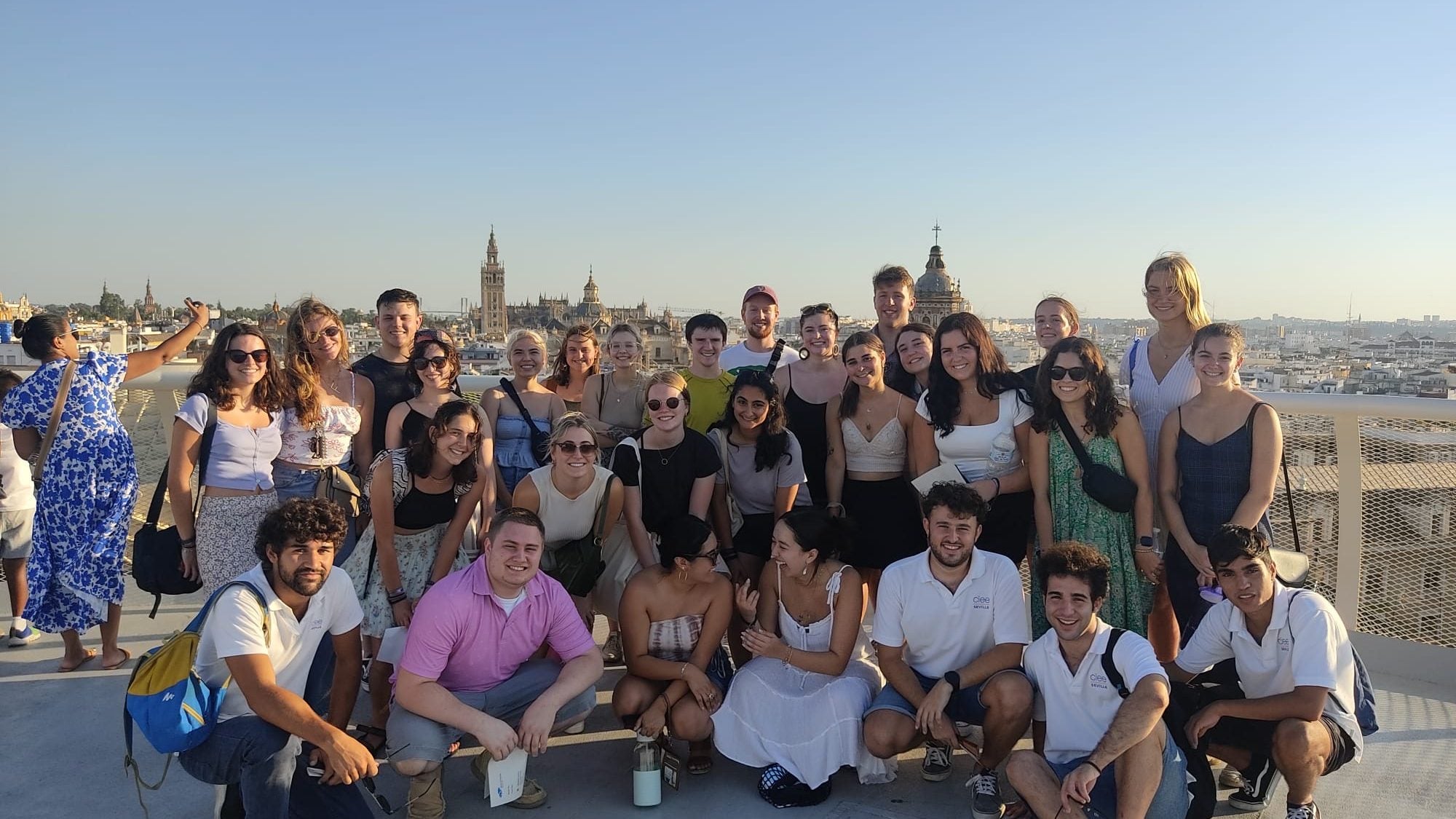 Study abroad students pose for a group photo with the city behind them