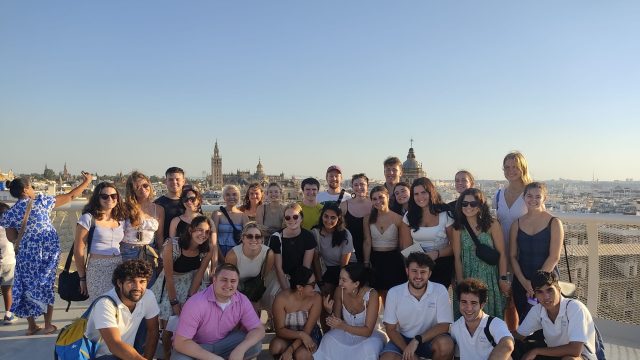 Study abroad students pose for a group photo with the city behind them