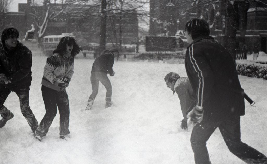 Black and white undated photograph of five Georgetown students having a snowball fight on Copley Lawn