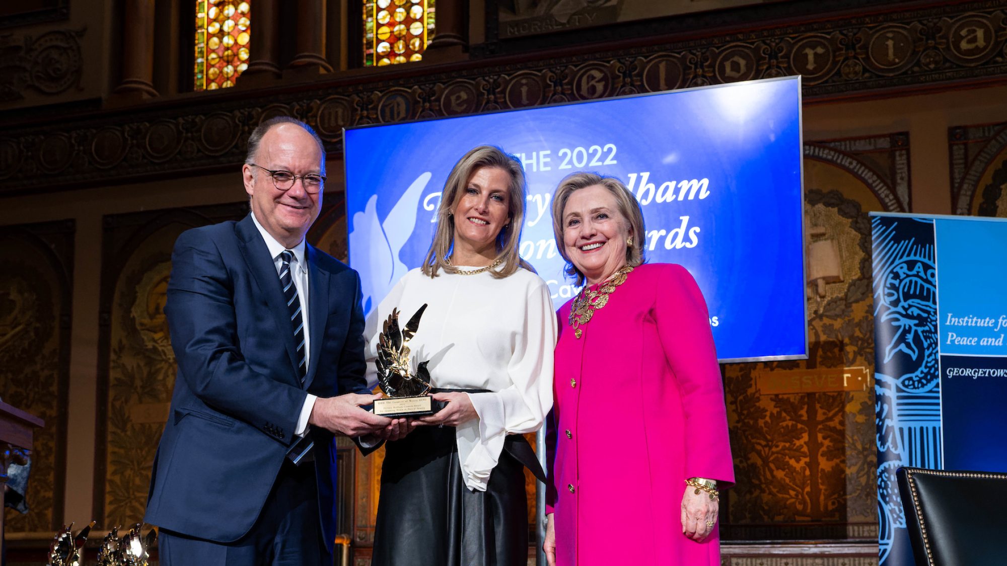 Jack DeGioia, The Countess of Wessex and Hillary Clinton hold an award onstage