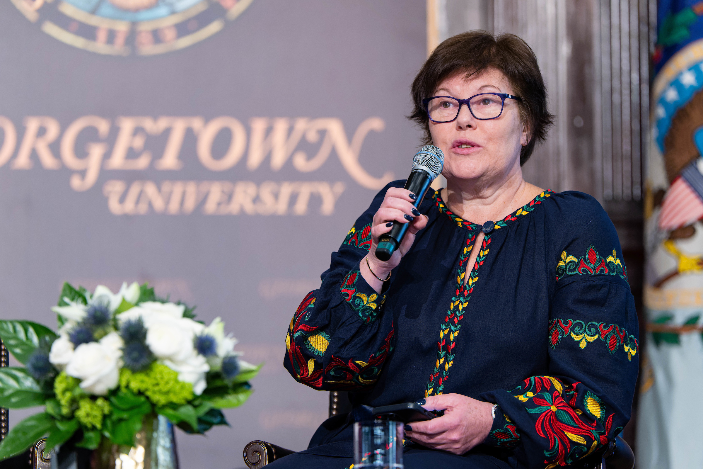 Kateryna Levchenko speaks into a microphone onstage with a Georgetown University sign in the background