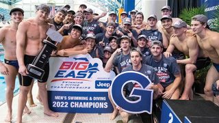 Men in bathing suits celebrating around a Georgetown &quot;G&quot; and &quot;2022 Champions&quot; sign