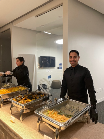 Caterers smile at camera with their dishes