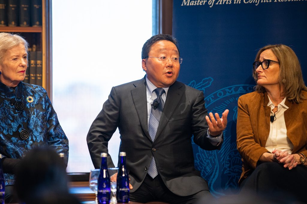 Elbadorj Tsakhia, the former president and prime minister of Mongolia, gestures with his one hand up while talking on a panel at a Georgetown event on Jan. 24. He wears clear glasses, a black suit, and a blue patterned tie.