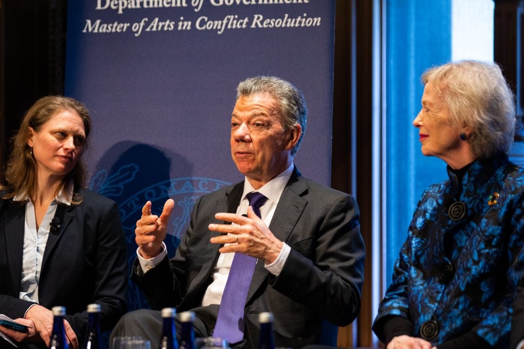 Juan Manuel Santos, the former president of Colombia, gestures with both hands while talking on a panel at Georgetown on Jan. 24. He is wearing a black suit, a white button-up shirt and a purple tie.