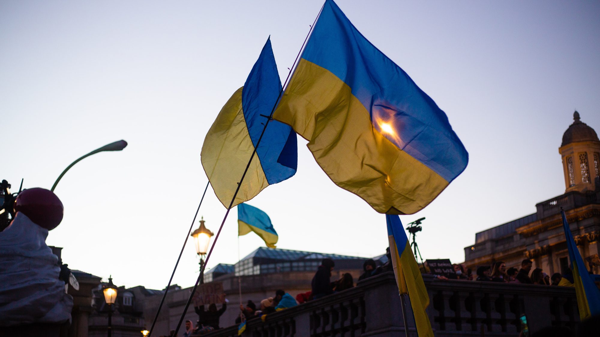 Ukrainian flags above protest scene.