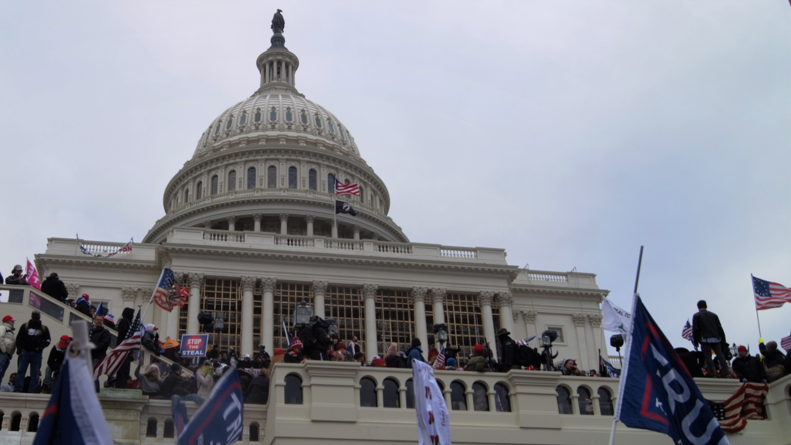 Protesters carrying &quot;Trump 2020&quot; crowd the steps to the U.S. Capitol building with the rotunda visible.