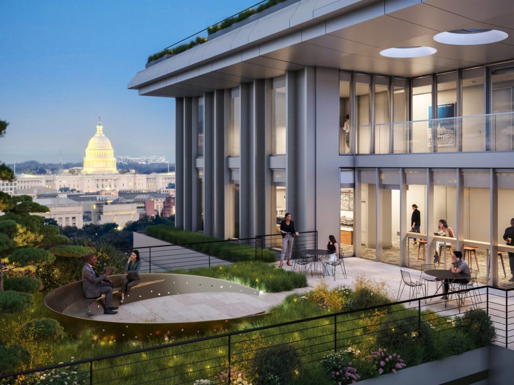 A rendering of the future home of the McCourt School of Public Policy, which shows a modern building with glass windows across the side and a garden and outdoor area to the left of the building. In the foreground is the U.S. Capitol, lit up with lights.