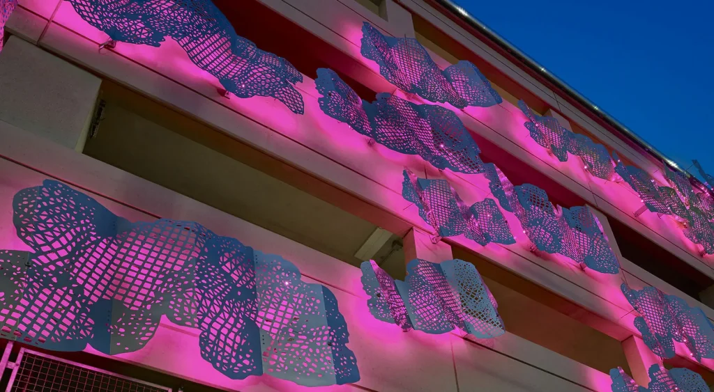 Parking garage with metal art pieces with purple backlighting.