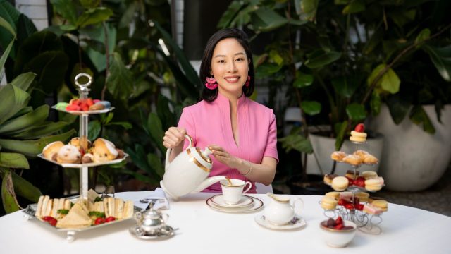 Sara Ho smiles as she pours tea while sitting at a table with pastries.
