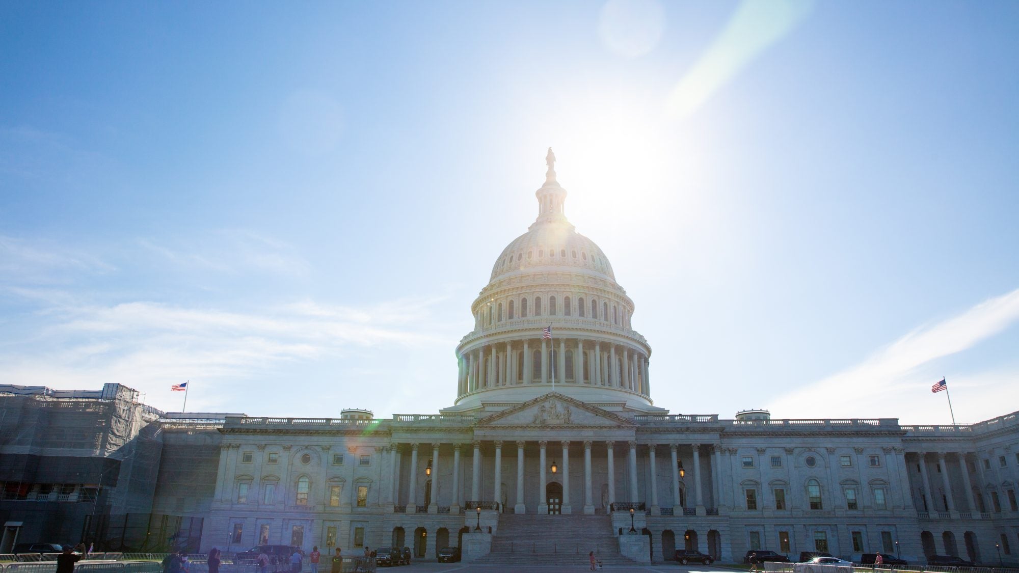 An image of the U.S. Capitol on a bright blue day. The sun illuminates the dome of the building.