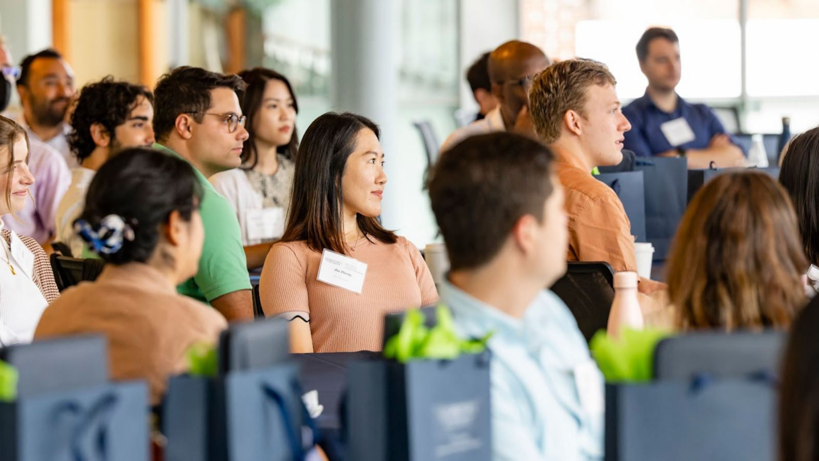 People sitting, listening to a program, wearing nametags.