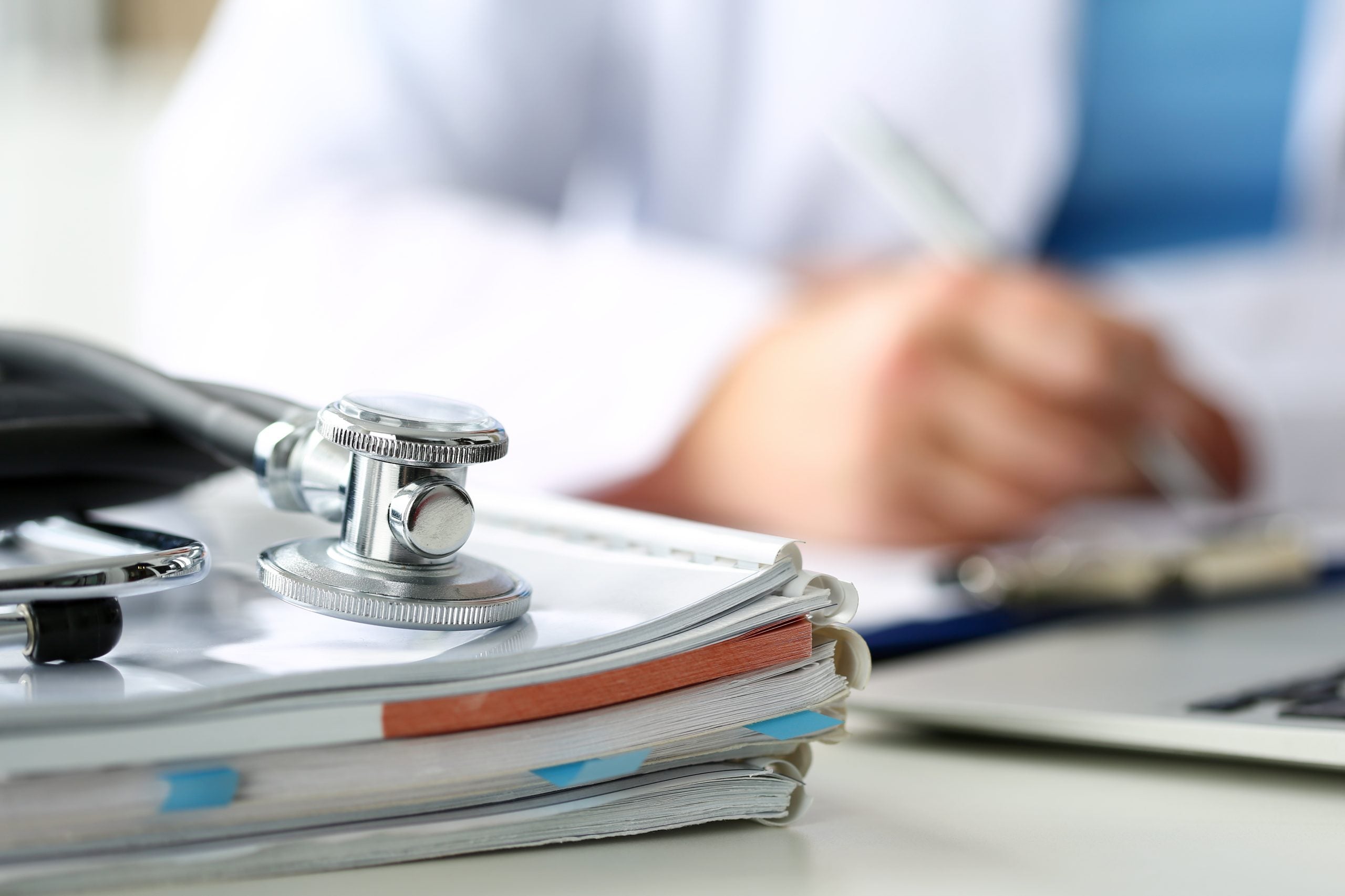 A stethoscope lies on a stack of notebooks and books
