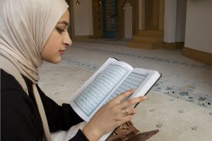 Aleena Maryam Dawer (H’24) sits on the floor and reads the Quran in the masjid. 