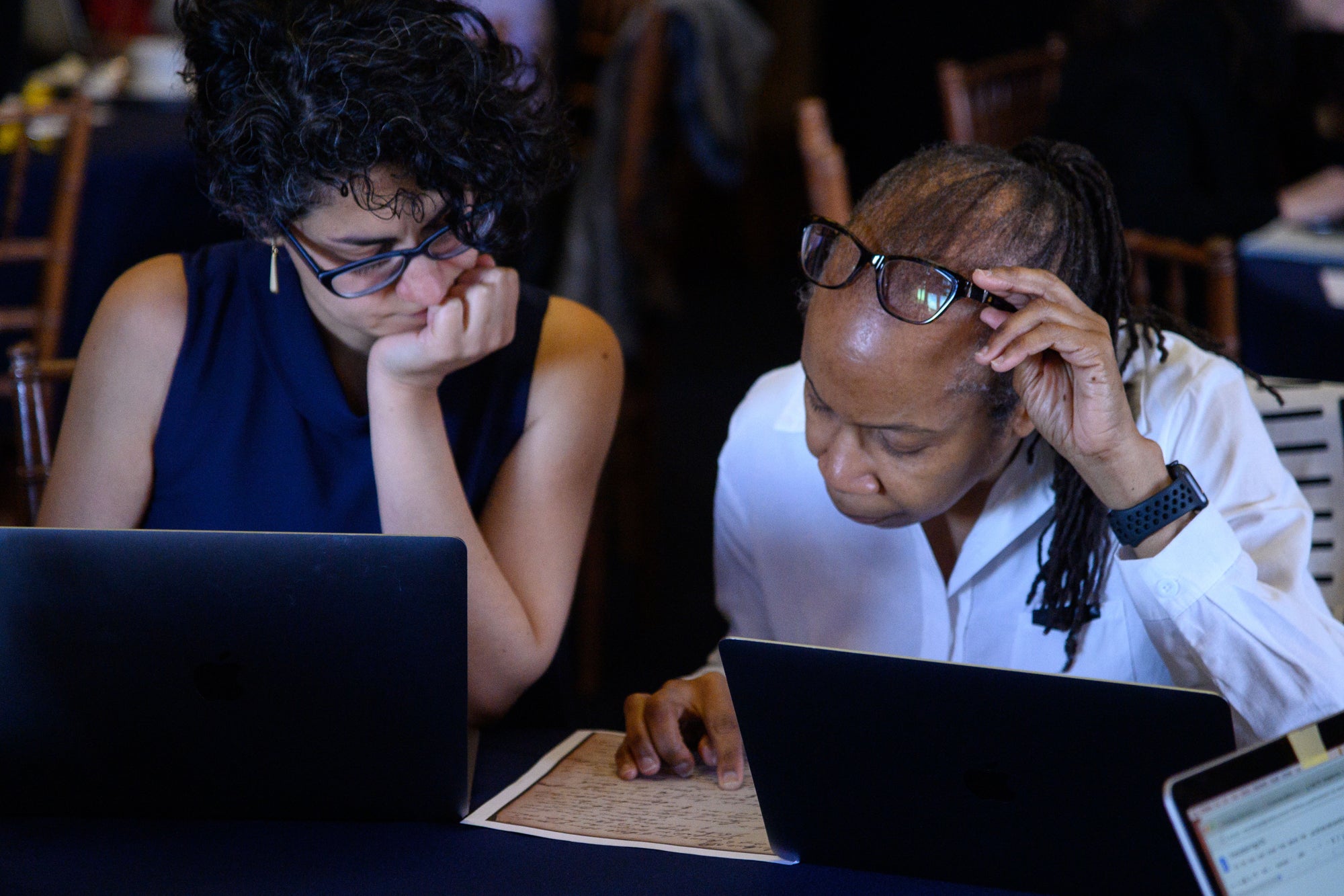 Two women look at an archived document at a transcription event hosted by the Georgetown Slavery Archive.