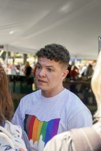 Jelenick pictured at Fresh Check Day as part of Suicide Prevention Awareness Month in October 2022 at the University of Dayton. He wears a gray T-shirt with a LGBTQ+ Pride flag decal on it.