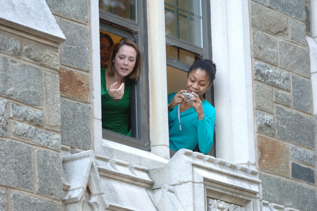 Students lean out of a Copley Hall window to take a picture of King Charles.