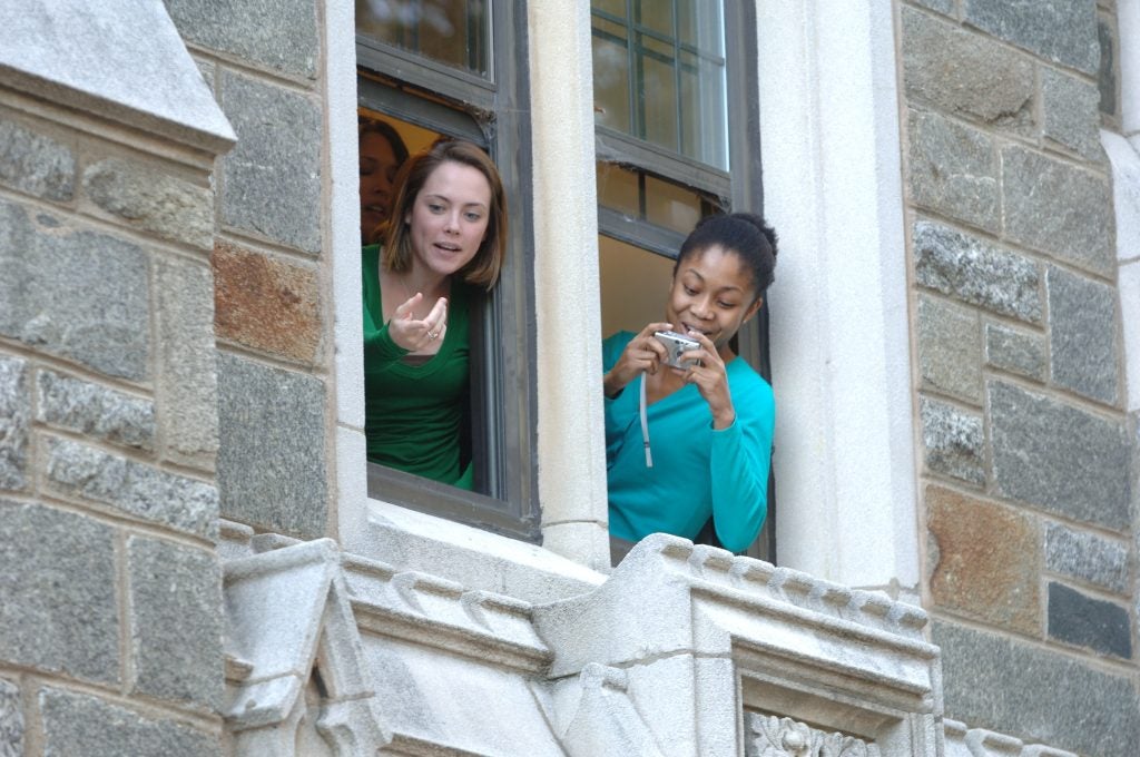 Students lean out of a Copley Hall window to take a picture of King Charles.