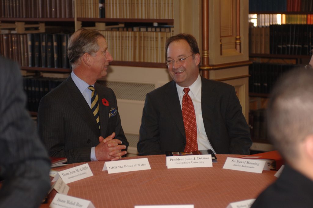 Georgetown President John J. DeGioia and King Charles are seated next to each other at an event in Riggs Library.