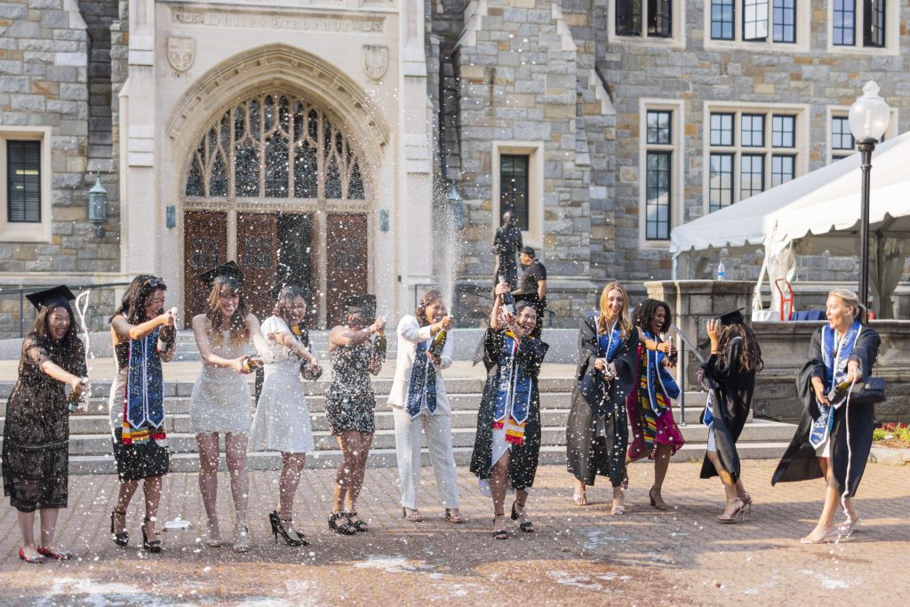 A group of female graduates popping bottles of champagne
