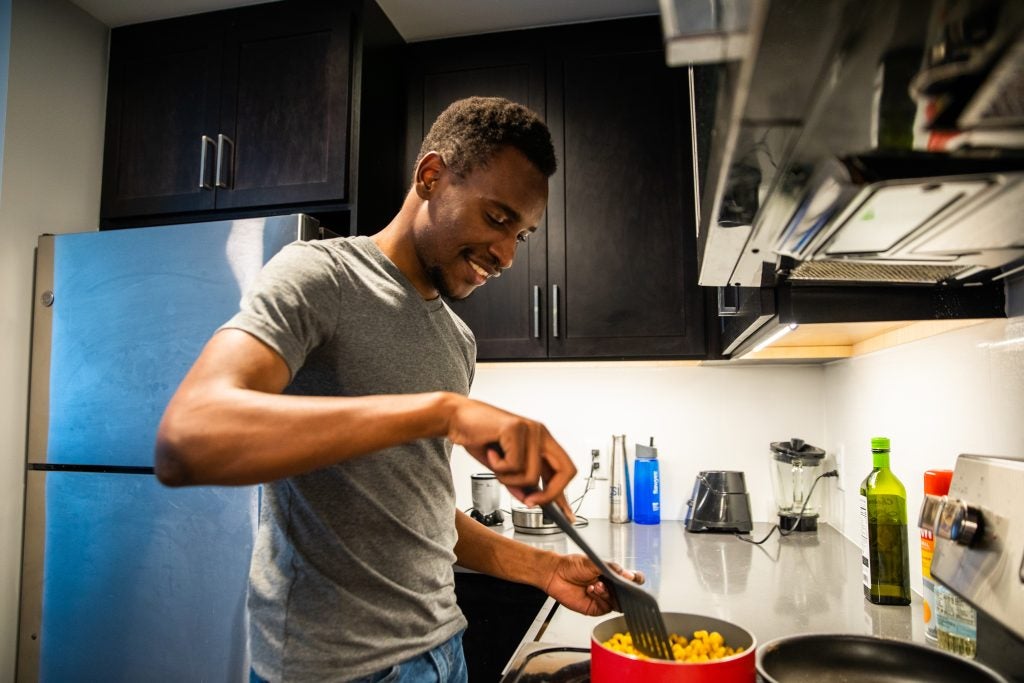 Gandawa cooks a pot of pasta in his apartment kitchen.