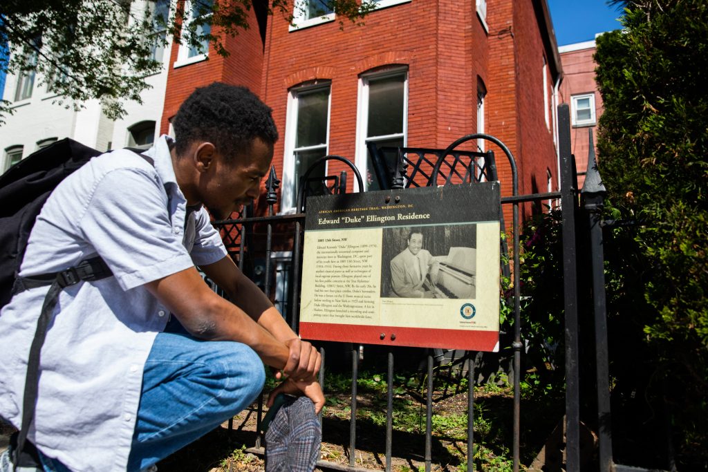 Gandawa reads a sign outside of Duke Ellington's home.