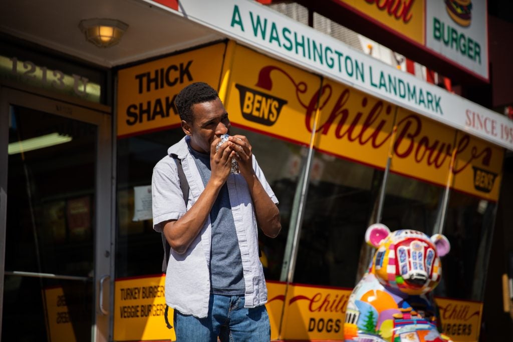 Gandawa eats a cheeseburger outside of Ben's Chili Bowl.