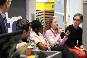 Leticia Bode, a professor at Georgetown, speaks on a fact-checking panel in Norway. She holds a microphone and raises both arms as she speaks.