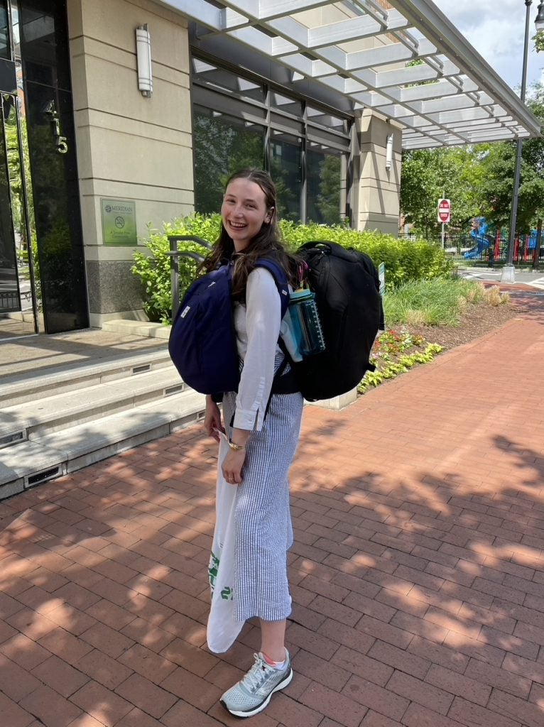 Hardy stands on the sidewalk with all of her backpacking gear.