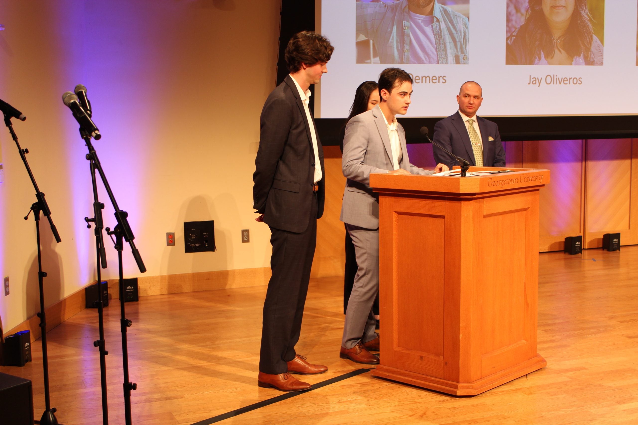 Cassera speaks at the podium on stage surrounded by his teammates.