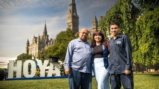 The Velasquez family stands in front of the Hoya Saxa sign on Georgetown&#039;s front lawn.