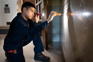 Reynaldo Velasquez uses a flashlight to peer into an HVAC system at a building on Georgetown's campus.