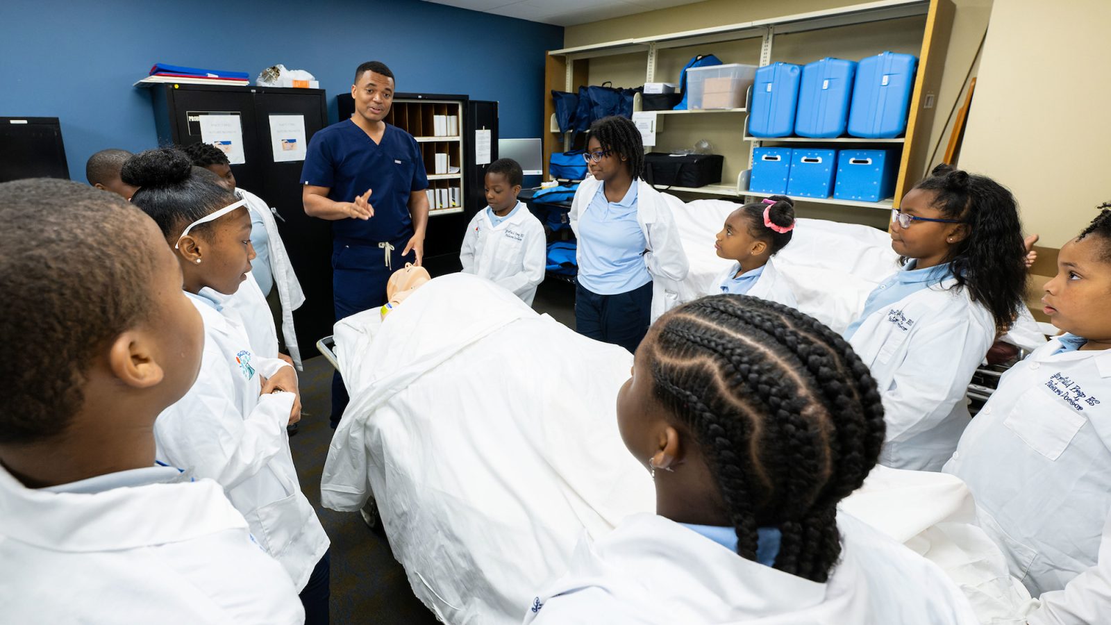 A group of fourth-grade students gather around a hospital bed for a medical discussion with first-year medical students at Georgetown.