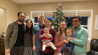 A group of student-parents and their babies in a home with a Christmas tree.