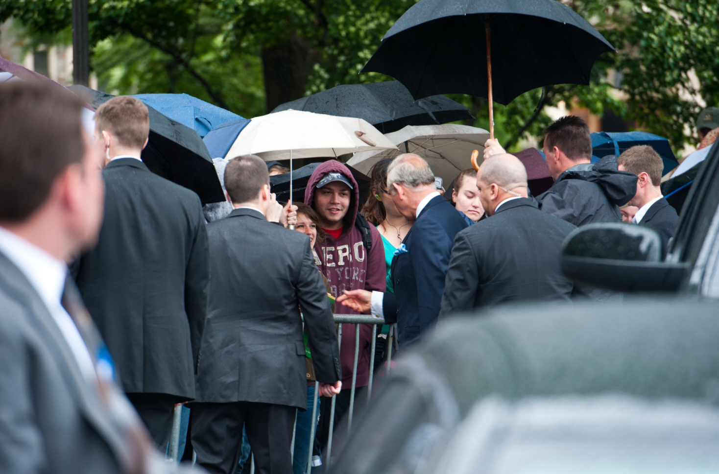 King Charles greets students waiting in the rain.