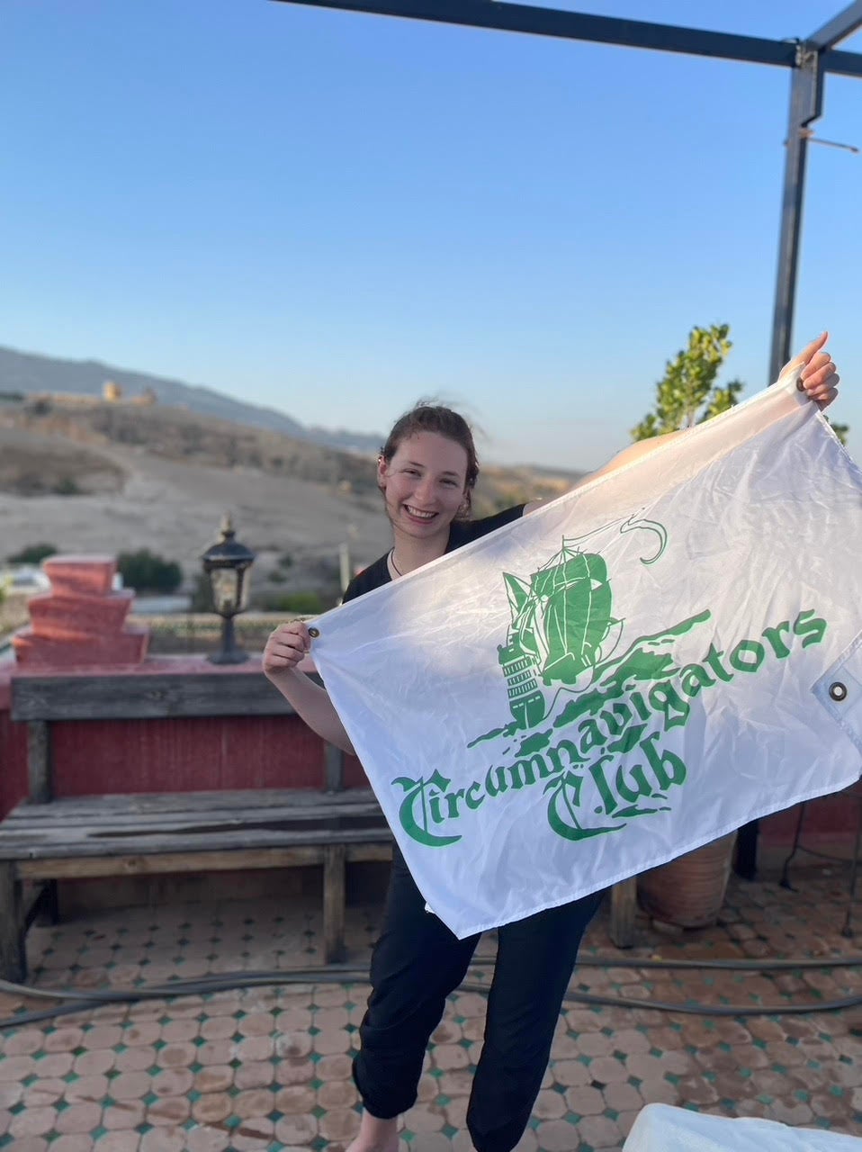 Emily Hardy somewhere in Morocco holding the Circumnavigators Club flag.