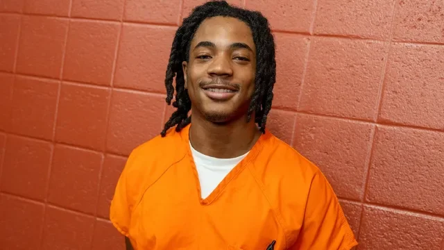 Georgetown Prison Scholar Keonte Lewis wears an orange jumpsuit in the DC jail, smiling at the camera.