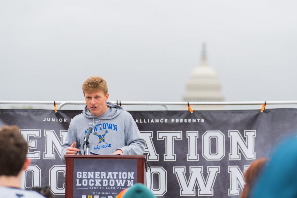 Jackson Mittleman (C'23) speaks at a rally for gun violence prevention. Behind him is a sign that says "Generation Lockdown" and the U.S. Capitol is in the foreground.