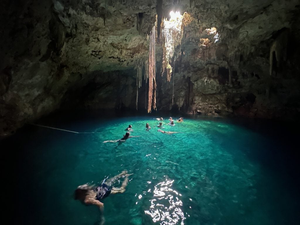 Students swimming in a sea cave with clear turquoise water