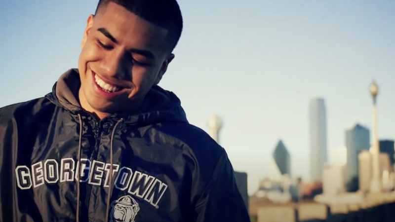 Adan Gonzalez wears a Georgetown sweatshirt and smiles with a city skyline behind him.