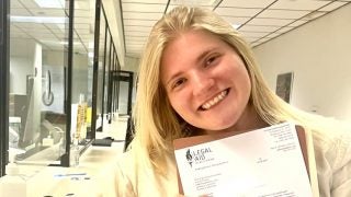 Student holding a legal document at a courthouse