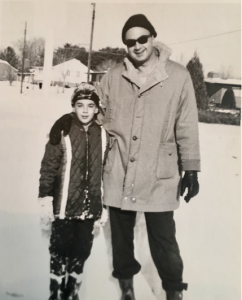 In this black-and-white photo, Harold Mintz (left) stands with his father (right) at a young boy outside on a snowy day. 