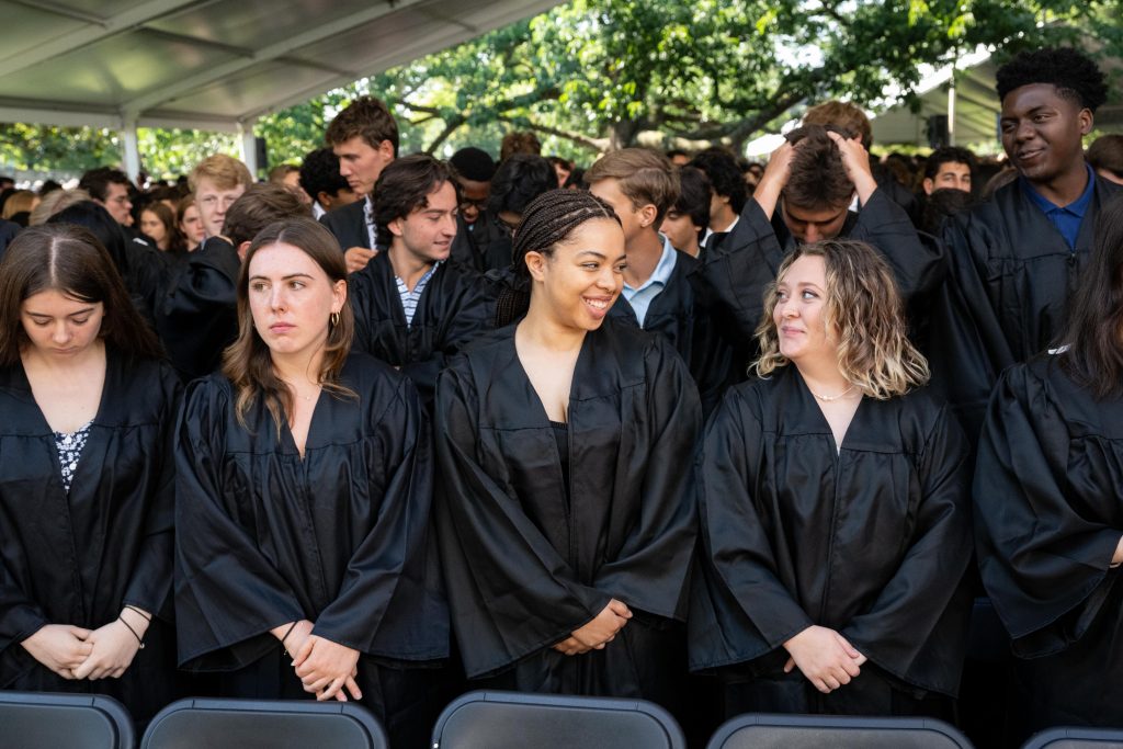 A group of female students smile at one another while standing in their black robes and New Student Convocation.