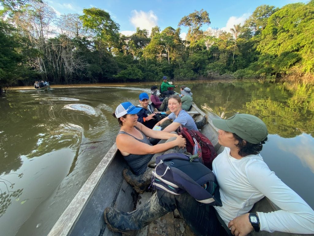 A group of people in a small motor boat going through a body of water